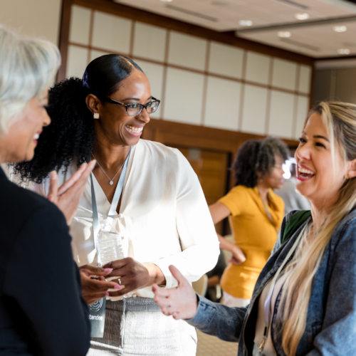 Three women stood chatting and smiling